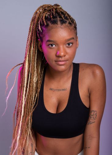 Brunette model with braids in her hair, wearing a black...