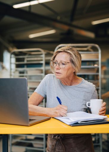 Focused senior female entrepreneur taking down notes...