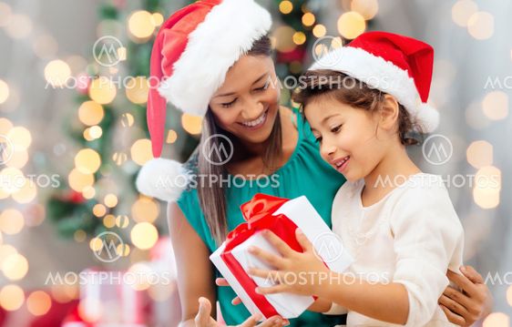 happy mother and girl in santa hats with gift box