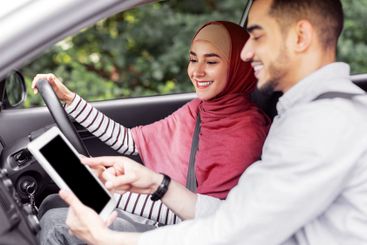 Happy millennial arab husband shows way on tablet to his...