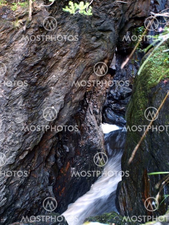 A waterfall between a rock in Scotland