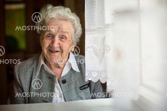 Positive elderly woman sitting in the room.