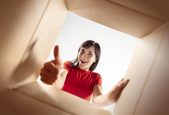 Woman unpacking and opening carton box and looking inside