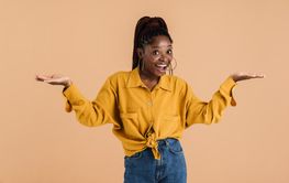 Young black woman with afro pigtails smiling and holding...
