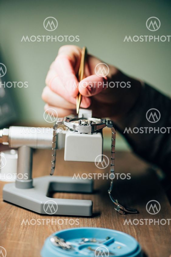 Cropped view of watchmaker repairing wristwatch by tool...