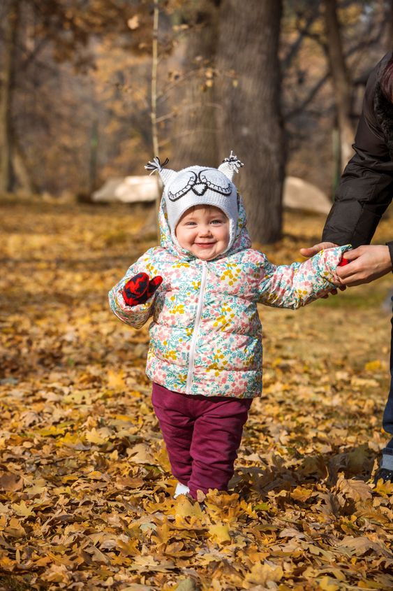 The little baby girl standing in autumn leaves