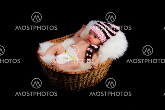 Newborn Child in a wicker basket on a black background.