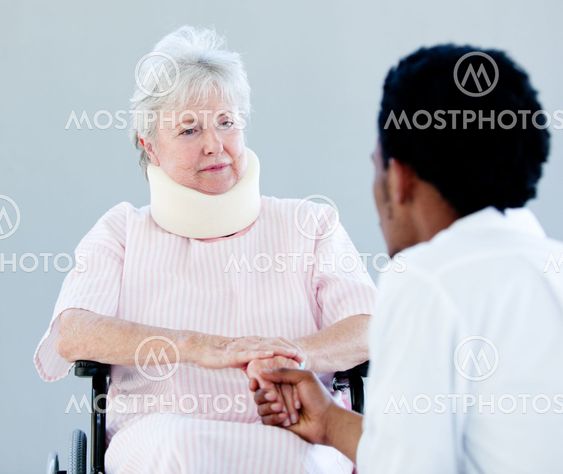 Senior woman sitting on a wheelchair with a neck brace talking with her doctor