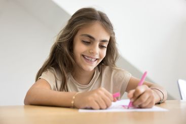 Closeup of little girl drawing with pink marker on paper