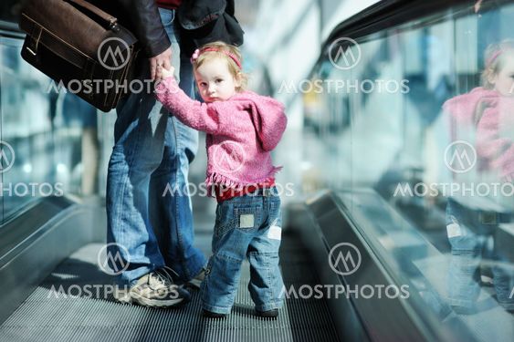 Toddler girl and her father on an escalator