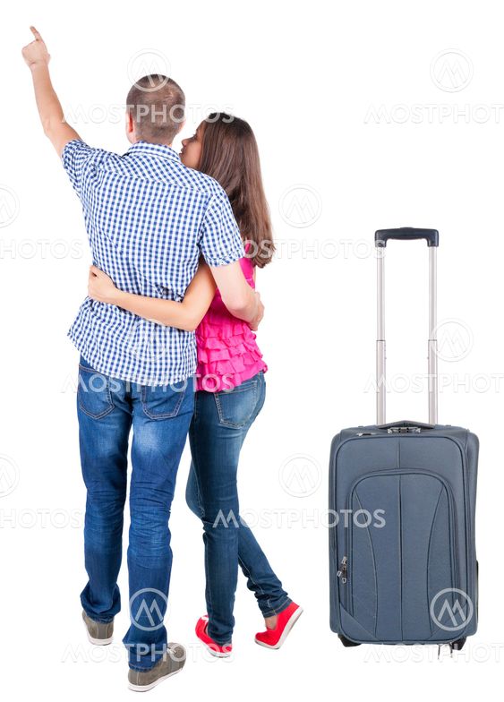 young couple traveling with suitcas and pointing at wal...