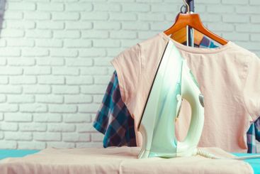 Iron on ironing board on light home interior background