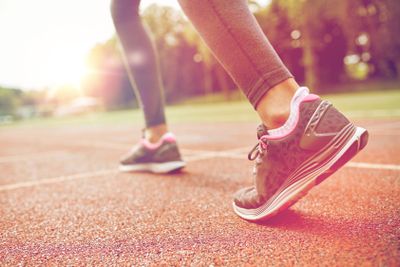 close up of woman feet running on track from back
