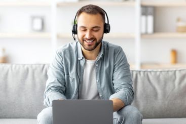 Smiling young Caucasian guy in headset making video call...