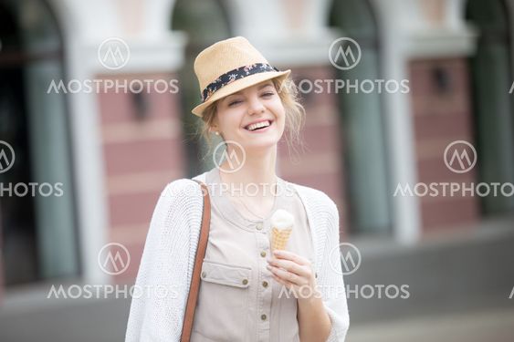 Headshot portrait of young happy woman eating ice-cream cone in summer