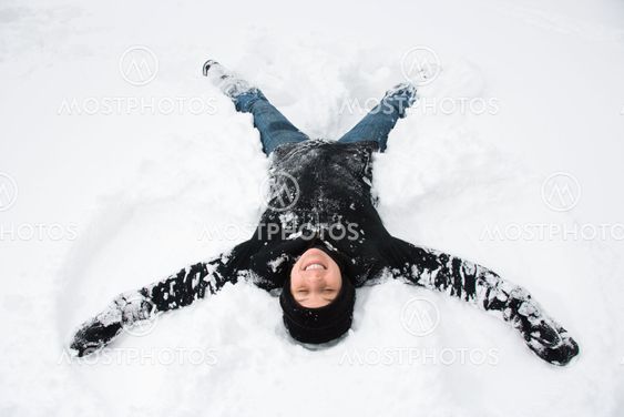 Woman making snow angel.