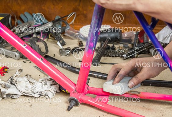 Hands of real bicycle mechanic sanding frame bike