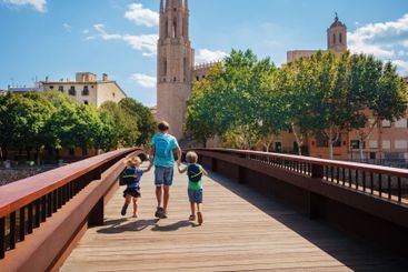 Children travelers with backpacks cross the bridge in...