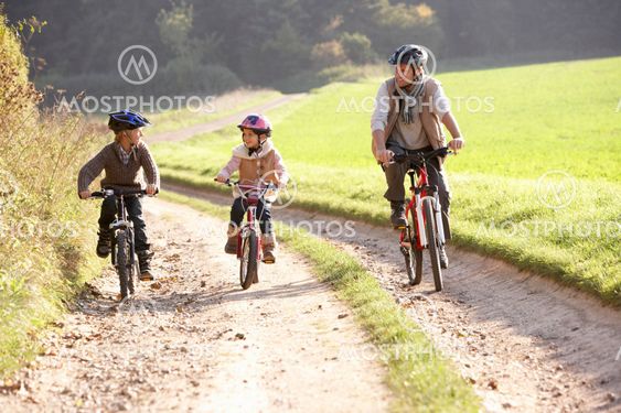 Young father with children ride bikes in park