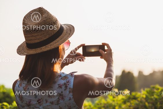 Young female tourist taking a photo of a beautiful sunset