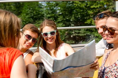 group of smiling friends traveling by tour bus