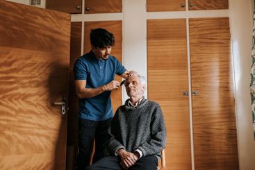 Male healthcare worker taking care of senior man sitting...