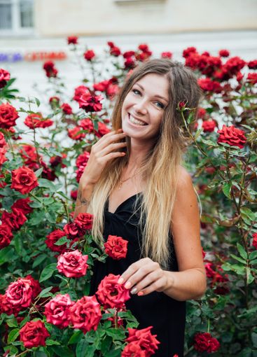 woman in black summer dress and many red rose flowers