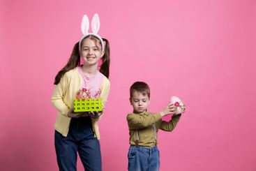 Little children presenting easter painted decorations in...