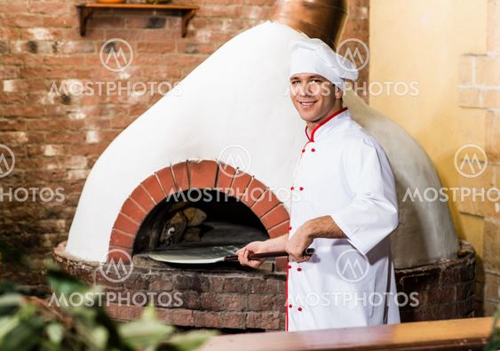 Chef puts dough in the oven for pizzas,