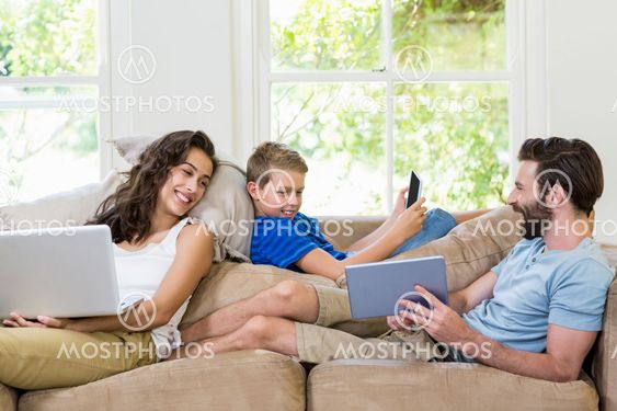 Parents and son using a laptop, tablet and phone