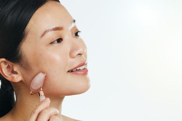 Asian woman, roller and face for skincare beauty,...