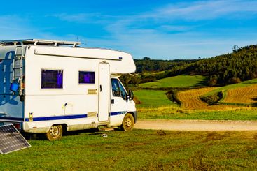 Camper with portable solar panel on coast
