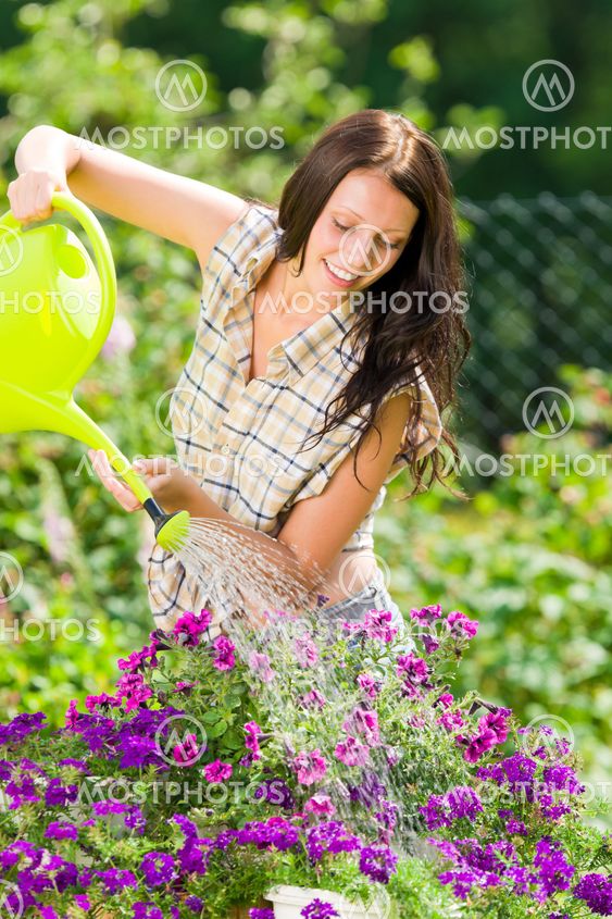 Gardening smiling woman watering can violet flower