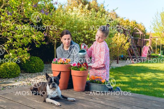 Mother and daughter planting flowers in pots in the...