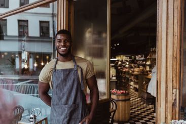 Portrait of smiling male owner standing outside store