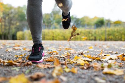 close up of young woman running in autumn park