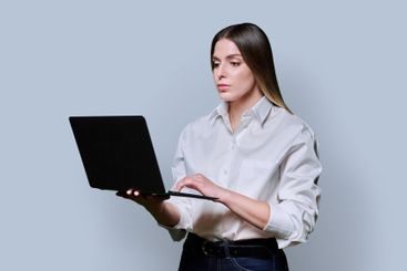 Young woman using laptop on grey studio background