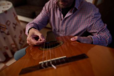 Close-up of a person tuning a classical guitar indoors