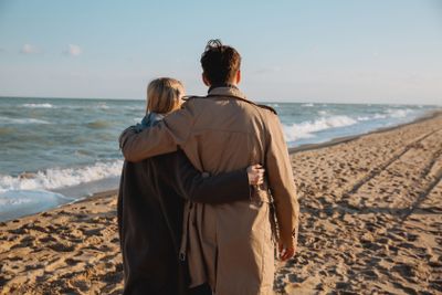 couple embracing and walking on seashore
