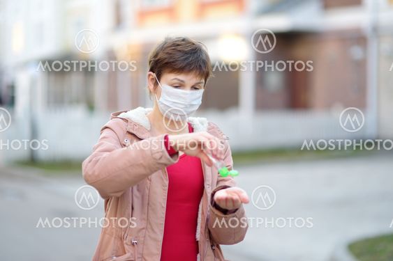 Mature woman wearing disposable medical face mask makes...