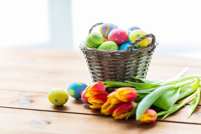 close up of easter eggs in basket and flowers