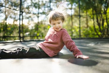 Little boy jumping on a trampoline in a backyard on warm...