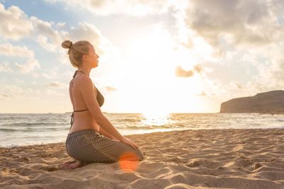 Woman relaxing on sea beach at sunset.