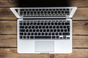 Laptop on wooden table showing keyboard details in a...