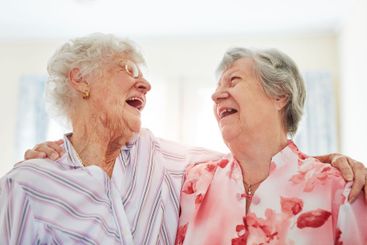 Friends, senior women and laugh in home with hug or joy...