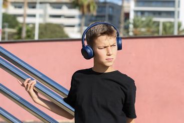 Handsome teenager standing with skateboard and listening...