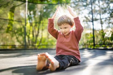 Little boy jumping on a trampoline in a backyard on warm...