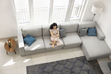 Woman sitting on large sofa with smartphone, above view