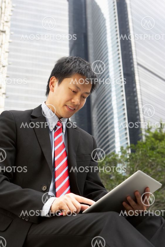 Chinese Businessman Working On Tablet Computer Outside Office