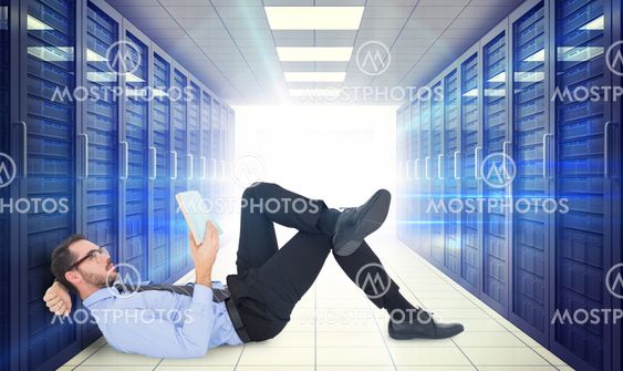 Composite image of businessman lying on the floor while reading a book
